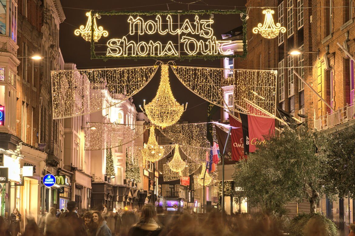 Dublin, Ireland – November 13. 2021: Beautiful evening view of Nollaig shona dhuit Christmas lights. Merry Christmas signboard written in Irish (Gaelic) language on Grafton Street. Crowded street
