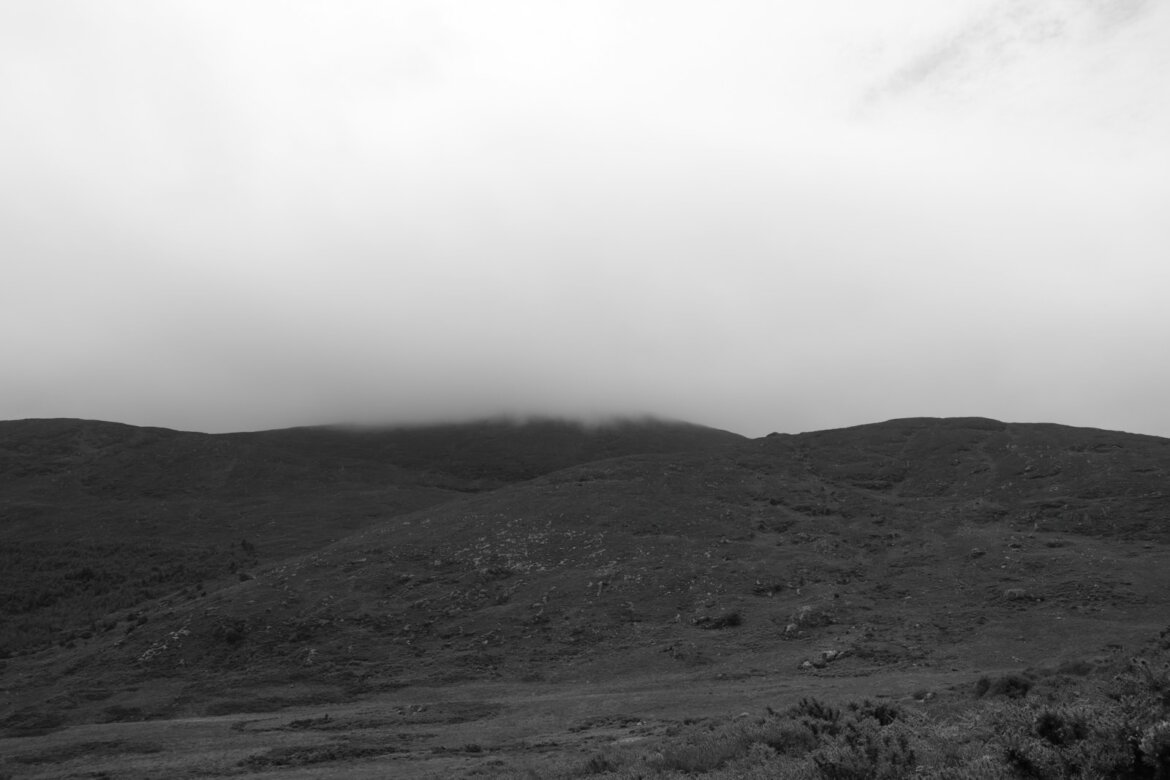 Hills are covered in mist and cloudy sky.