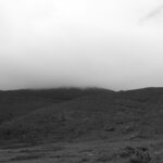 Hills are covered in mist and cloudy sky.