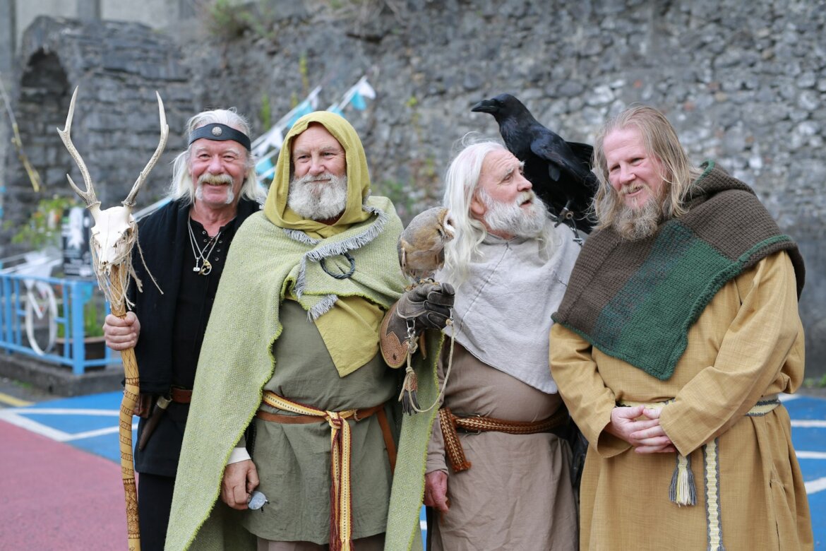 Four men in historical costumes with a raven