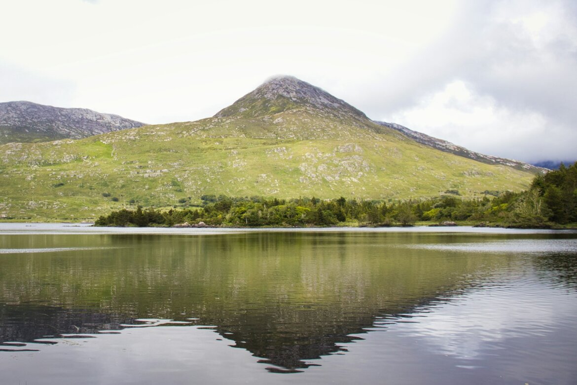 Mountain reflected in a calm lake under cloudy sky