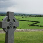 gray concrete cross on grass field during day