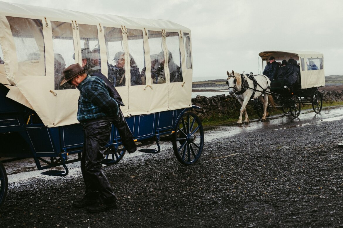 Horse-drawn carriages on a wet, rural road.