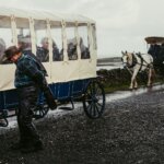 Horse-drawn carriages on a wet, rural road.