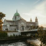 Stone cathedral with green dome by river and river