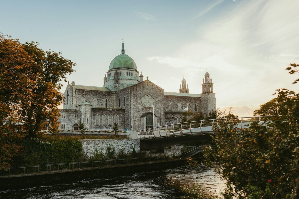Stone cathedral with green dome by river and river