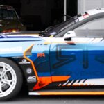 A custom race car is shown in a garage.