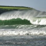 green grass field beside sea waves during daytime