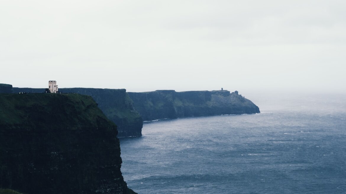 Cliffs meet the sea under a cloudy sky.