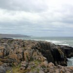 a rocky cliff with a body of water in the background