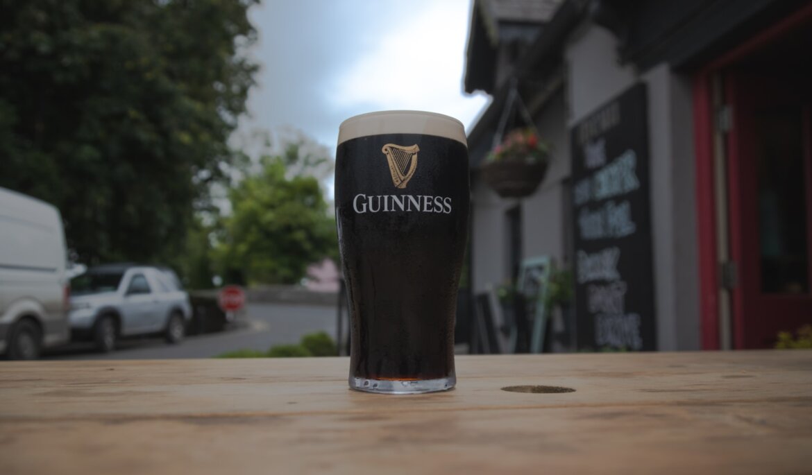 a pint of guinness on a table outside a pub