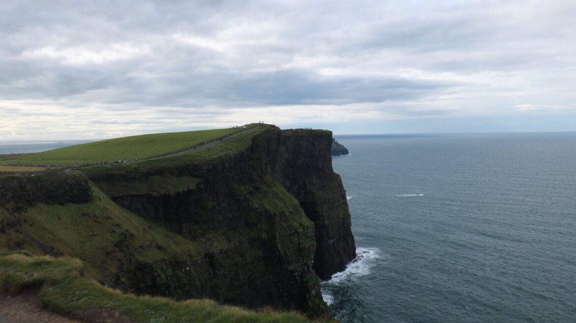 a cliff overlooking the ocean on a cloudy day