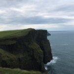 a cliff overlooking the ocean on a cloudy day