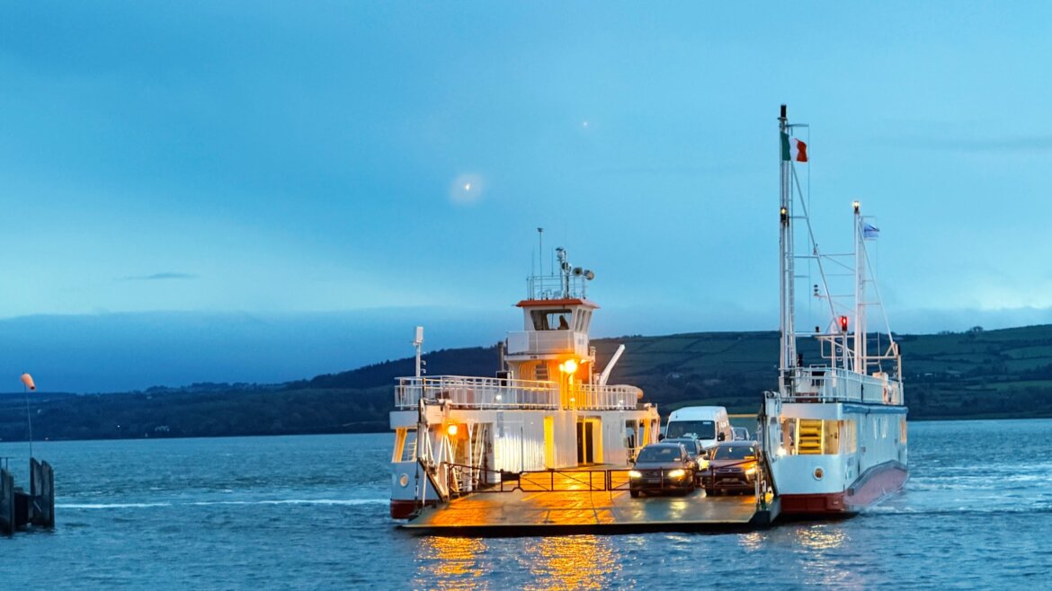 Ferry boat carrying cars across water at dusk